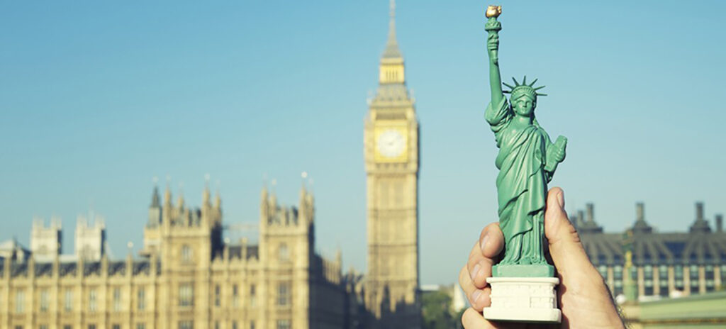 A photo of a person holding a Statue of Liberty figurine with Big Ben in the background