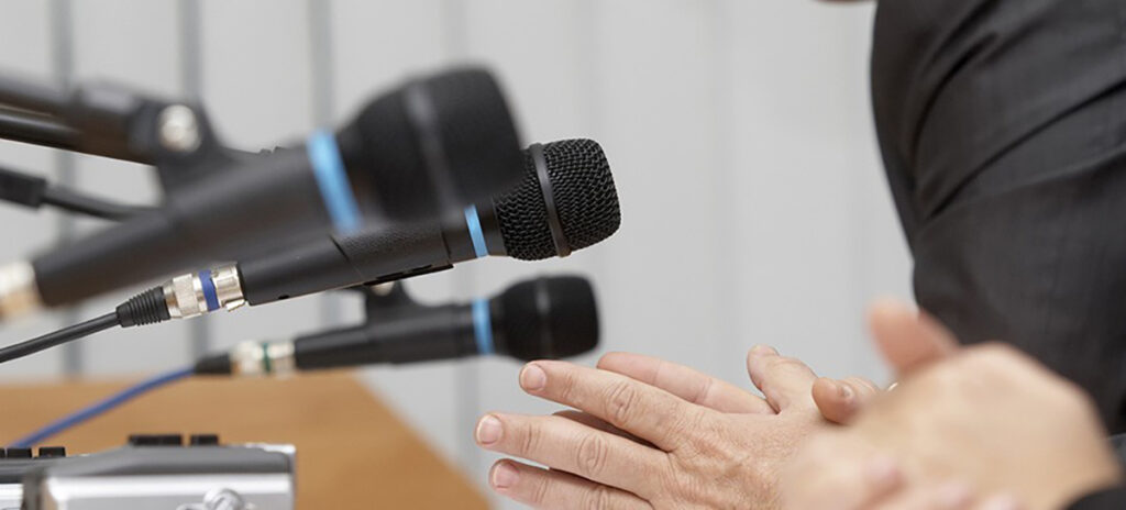 A person speaking into a cluster of microphones