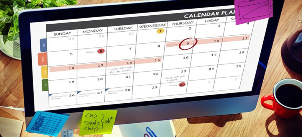 A photo of a desktop computer covered with sticky notes, displaying a calendar