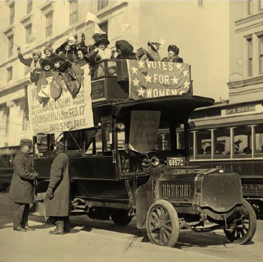 Black and white photograph of suffragettes promoting voting rights for women in an antique car