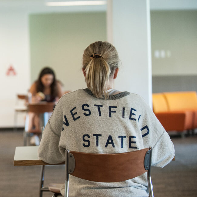 A female student studying and wearing a Westfield State sweatshirt