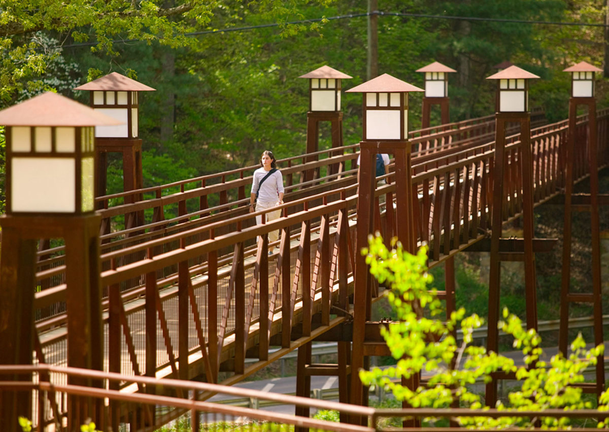 A female Warren Wilson College student crossing a pedestrian bridge