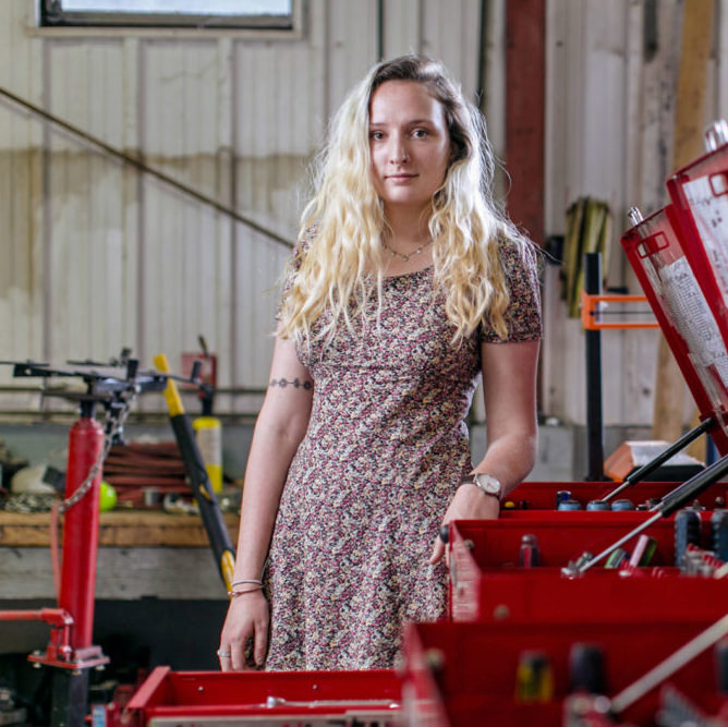 Young woman stands by row of open tool chests
