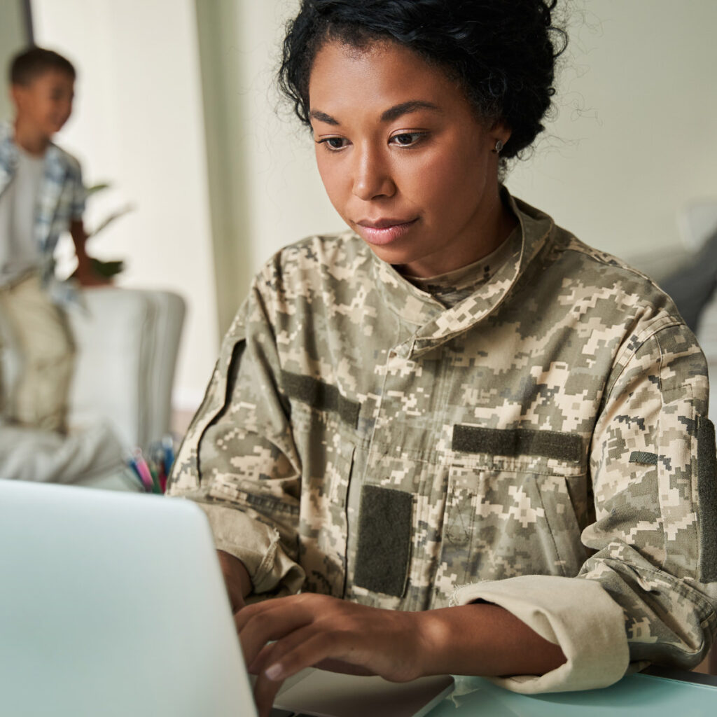 A woman in fatigues working on a laptop