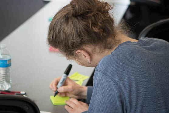 A woman writes on a sticky note with a marker during a workshop