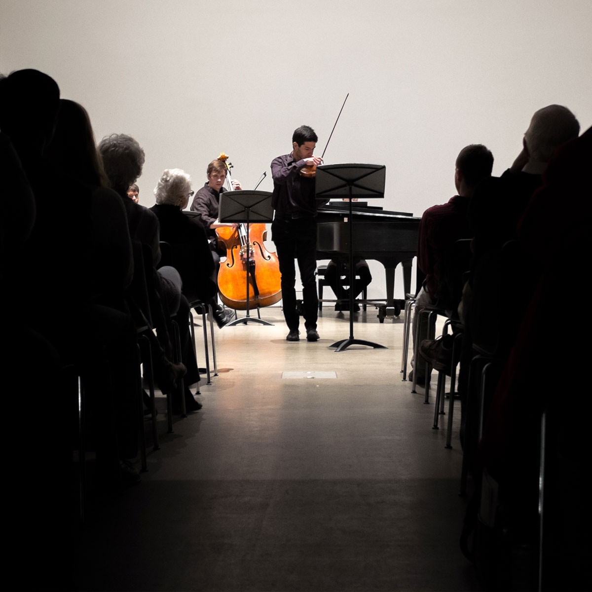 Two students, one playing violin and the other playing cello, perform for an audience
