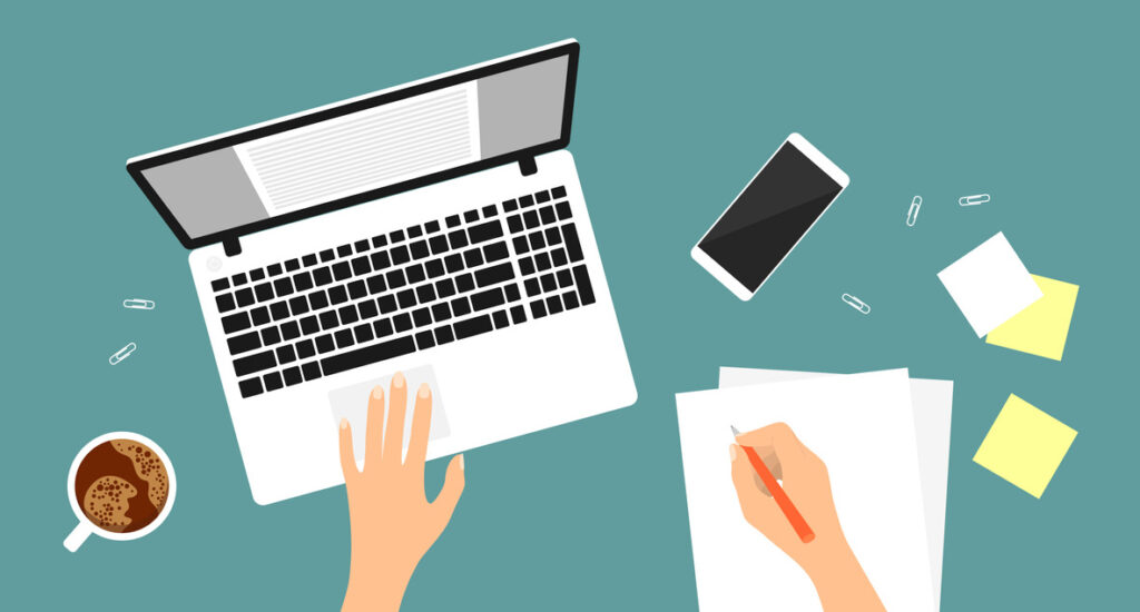 A hand writing on a piece of paper, a laptop, a smartphone, notes, a cup of coffee on a blue background. Top view of the workplace.