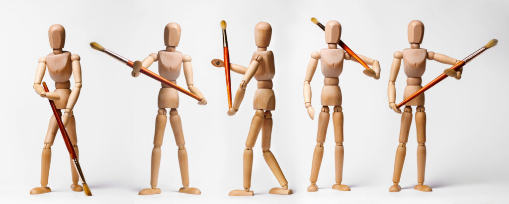Painter's wooden models holding paintbrushes in different poses